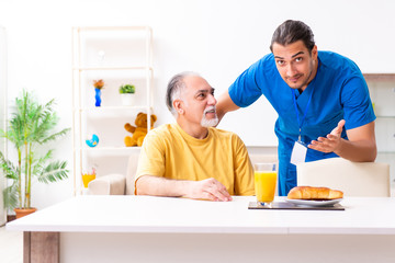 Young male doctor visiting old patient at home