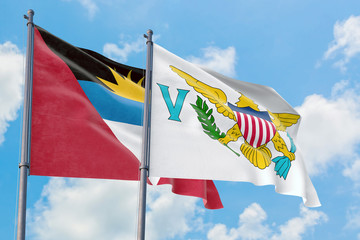 United States Virgin Islands and Antigua and Barbuda flags waving in the wind against white cloudy blue sky together. Diplomacy concept, international relations.