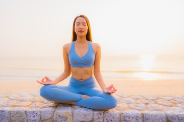 Fototapeta na wymiar Portrait young asian woman do meditation around sea beach ocean at sunrise