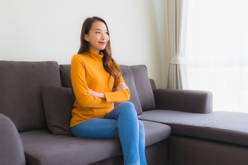 Portrait young asian woman happy relax smile on sofa chair with pillow in living room