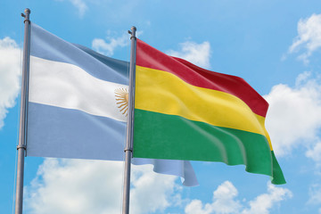 Bolivia and Argentina flags waving in the wind against white cloudy blue sky together. Diplomacy concept, international relations.