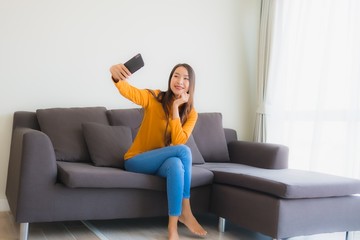 Obraz premium Portret młodej kobiety azjatyckie za pomocą inteligentnego telefonu komórkowego na kanapie z poduszką w salonie