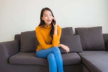 Portrait young asian woman using smart mobile phone on sofa with pillow in living room