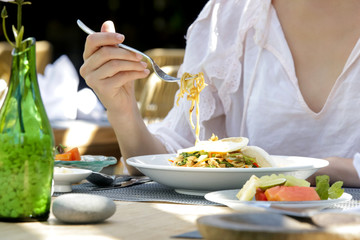 Woman eating noodle, summertime lunch break, close up image of woman enjoying healthy meal