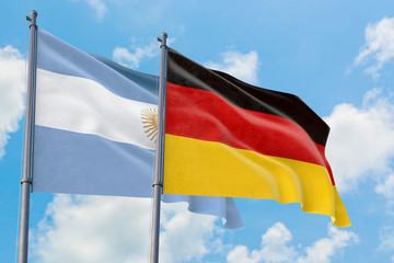 Germany and Argentina flags waving in the wind against white cloudy blue sky together. Diplomacy concept, international relations.