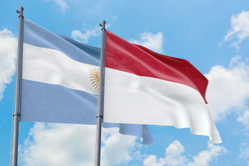 Indonesia and Argentina flags waving in the wind against white cloudy blue sky together. Diplomacy concept, international relations.