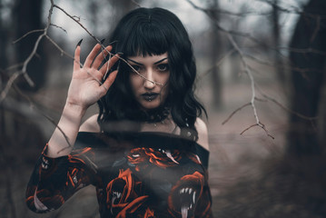 Young beautiful gothic enchantress in the forest
