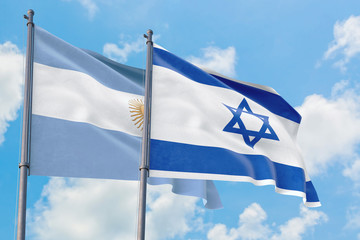 Israel and Argentina flags waving in the wind against white cloudy blue sky together. Diplomacy concept, international relations.