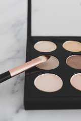 close-up of brush on top of eyeshadow palette with trendy nudes and bronzy tones