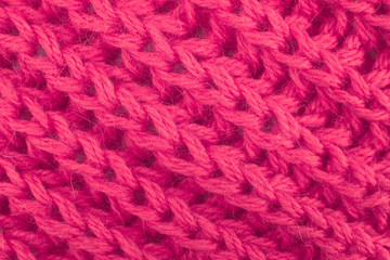 Close up of a knitted wool pattern. Close-up of a fragment of a knitted warm scarf. Thick red wool yarn.