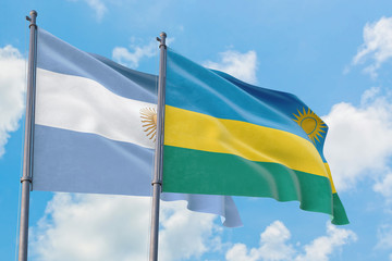 Rwanda and Argentina flags waving in the wind against white cloudy blue sky together. Diplomacy concept, international relations.