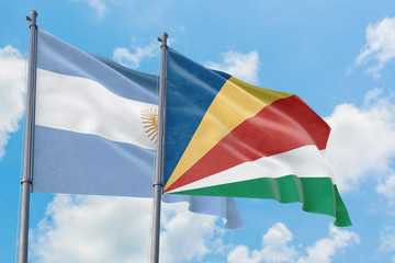 Seychelles and Argentina flags waving in the wind against white cloudy blue sky together. Diplomacy concept, international relations.