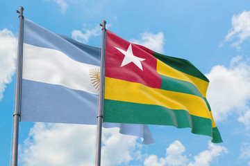 Togo and Argentina flags waving in the wind against white cloudy blue sky together. Diplomacy concept, international relations.