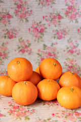 Ein Berg oranger Mandarinen auf vintage Untergrund mit Blumen und Rosen