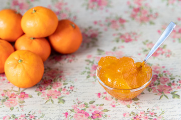 frische orange Mandarinenmarmelade in Schüssel auf vintage Untergrund mit Rosen und Blumen