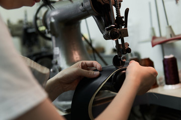 ミシンで革を縫う女性の手元 - obrazy, fototapety, plakaty