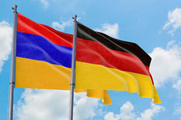 Germany and Armenia flags waving in the wind against white cloudy blue sky together. Diplomacy concept, international relations.