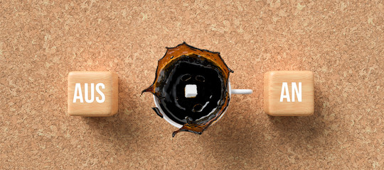 cup of coffee and cubes with German words for ON and OFF on cork background