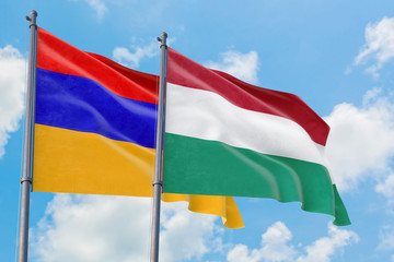 Hungary and Armenia flags waving in the wind against white cloudy blue sky together. Diplomacy concept, international relations.