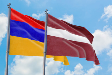 Latvia and Armenia flags waving in the wind against white cloudy blue sky together. Diplomacy concept, international relations.