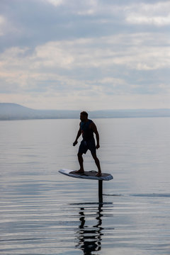 Man riding an electric hydrofoil foil board on a lake with a life jacket