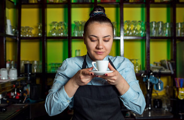 Portrait of female barista holding cup of coffee