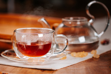 Cup of hot tea with rock sugar, dry leaves served in thermo glass cup