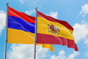 Spain and Armenia flags waving in the wind against white cloudy blue sky together. Diplomacy concept, international relations.