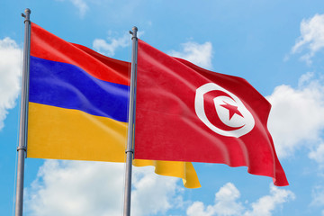 Tunisia and Armenia flags waving in the wind against white cloudy blue sky together. Diplomacy concept, international relations.