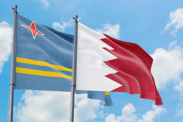 Bahrain and Aruba flags waving in the wind against white cloudy blue sky together. Diplomacy concept, international relations.
