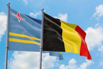 Belgium and Aruba flags waving in the wind against white cloudy blue sky together. Diplomacy concept, international relations.