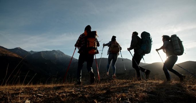 Group of four young people having a hiking tour, going for trekking adventure together, reaching top of mountain and cheering - friendship, achievement concept 4k footage