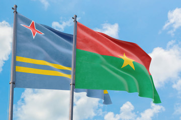 Burkina Faso and Aruba flags waving in the wind against white cloudy blue sky together. Diplomacy concept, international relations.