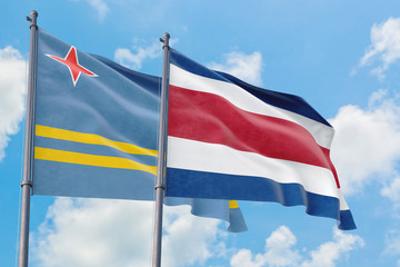 Costa Rica and Aruba flags waving in the wind against white cloudy blue sky together. Diplomacy concept, international relations.