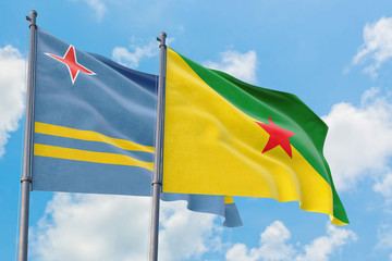 French Guiana and Aruba flags waving in the wind against white cloudy blue sky together. Diplomacy concept, international relations.