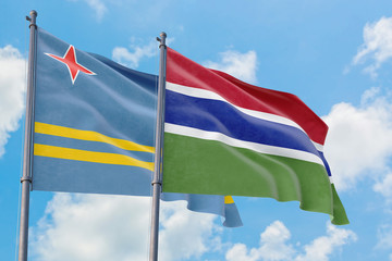 Gambia and Aruba flags waving in the wind against white cloudy blue sky together. Diplomacy concept, international relations.