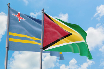 Guyana and Aruba flags waving in the wind against white cloudy blue sky together. Diplomacy concept, international relations.