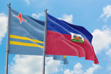 Haiti and Aruba flags waving in the wind against white cloudy blue sky together. Diplomacy concept, international relations.