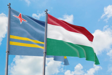 Fototapeta na wymiar Hungary and Aruba flags waving in the wind against white cloudy blue sky together. Diplomacy concept, international relations.