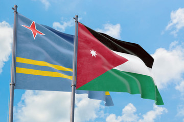 Jordan and Aruba flags waving in the wind against white cloudy blue sky together. Diplomacy concept, international relations.