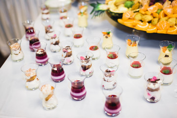 Delicious and tasty dessert table with cupcakes and shots at reception closeup