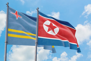 North Korea and Aruba flags waving in the wind against white cloudy blue sky together. Diplomacy concept, international relations.