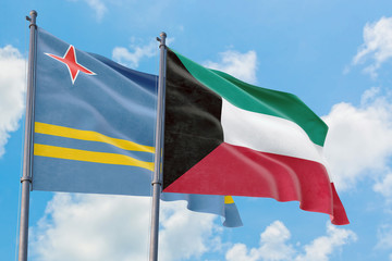 Kuwait and Aruba flags waving in the wind against white cloudy blue sky together. Diplomacy concept, international relations.