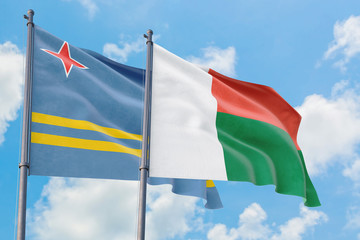 Madagascar and Aruba flags waving in the wind against white cloudy blue sky together. Diplomacy concept, international relations.