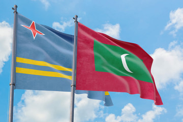 Maldives and Aruba flags waving in the wind against white cloudy blue sky together. Diplomacy concept, international relations.