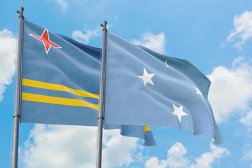 Micronesia and Aruba flags waving in the wind against white cloudy blue sky together. Diplomacy concept, international relations.