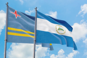 Nicaragua and Aruba flags waving in the wind against white cloudy blue sky together. Diplomacy concept, international relations.