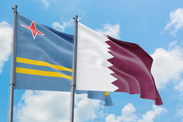 Qatar and Aruba flags waving in the wind against white cloudy blue sky together. Diplomacy concept, international relations.