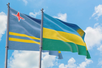 Rwanda and Aruba flags waving in the wind against white cloudy blue sky together. Diplomacy concept, international relations.