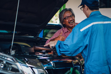 gargae customer and car mechanic together investigate maintenance and repair programe at garage and...